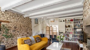 A cozy living room with a yellow sofa, a white coffee table, and a bookshelf filled with books.