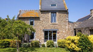 A stone house with a grey roof, a small window, and a door.