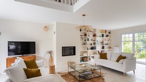 Un salon moderne avec un canapé blanc, une table basse en verre et un grand téléviseur à écran plat.