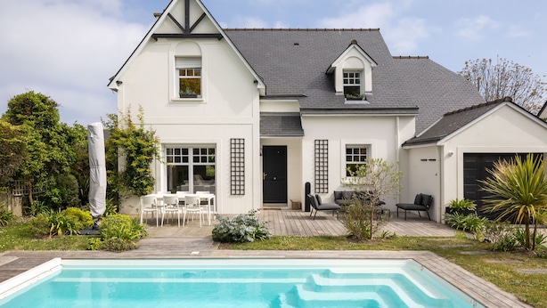 Une maison à deux étages avec une piscine, un patio doté de mobilier d’extérieur et un jardin bien entretenu.