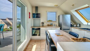 Una cocina compacta con comedor, una puerta corrediza de vidrio que da a un patio y un horno empotrado.