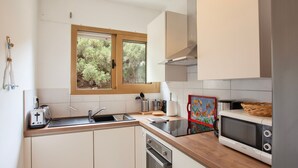 A modern kitchen with white cabinets, a stainless steel dishwasher, a microwave, and a wooden countertop. - Alivi - Appt climatisé avec vue mer et montagne (L'Île-Rousse)