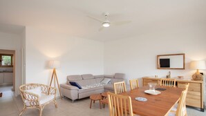 A room with a wooden dining table, chairs, a sofa, and a ceiling fan. - Alivi - Appt climatisé avec vue mer et montagne (L'Île-Rousse)