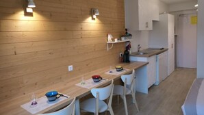 Een moderne keuken met houten wanden, witte kasten en een lange toonbank met stoelen.