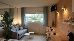 Een moderne, compacte woonruimte met een bank, een eettafel en een keukenhoek.