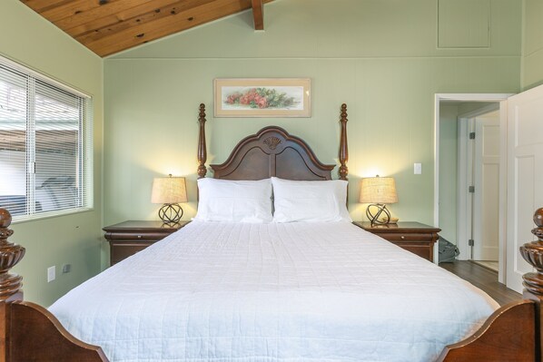 A neatly made bed with a wooden headboard, two bedside tables with lamps, and a framed floral artwork on the wall. - Hollie's Hideaway: 3 BR, 3 BA House in Cambria, Sleeps 6 (Cambria)