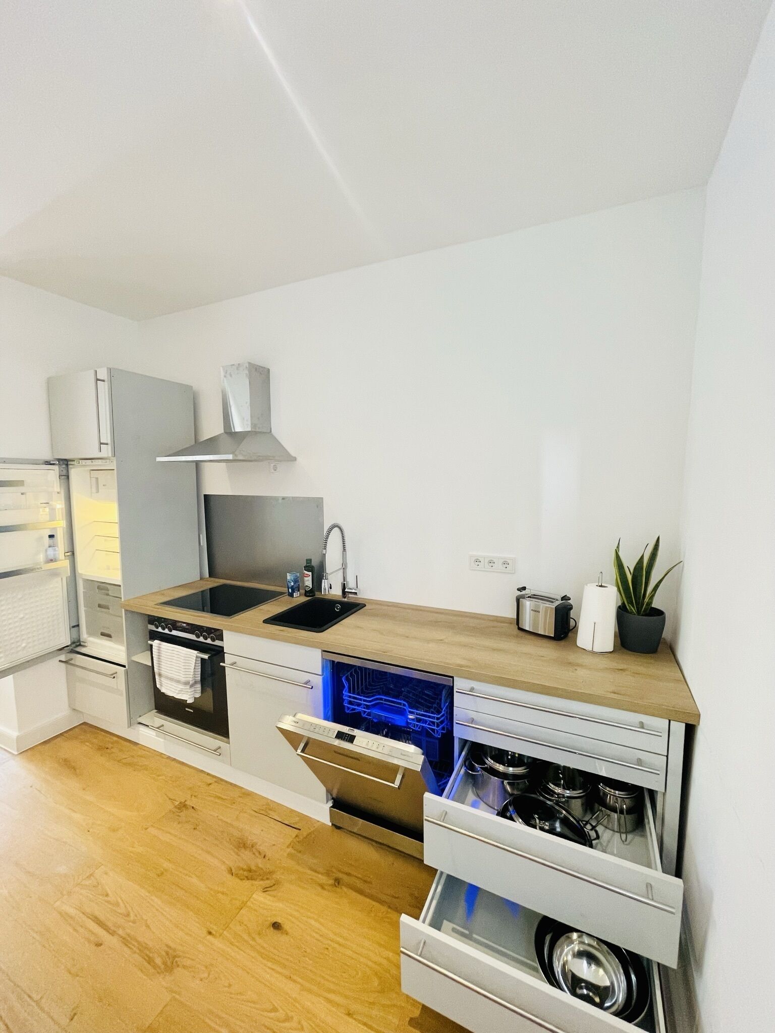 A compact kitchen with a built-in oven, a microwave, a sink, and a dishwasher.