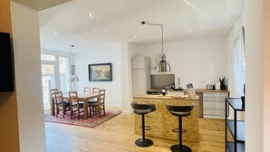 Una cocina moderna con una isla central, taburetes de bar y un comedor con mesa y sillas.