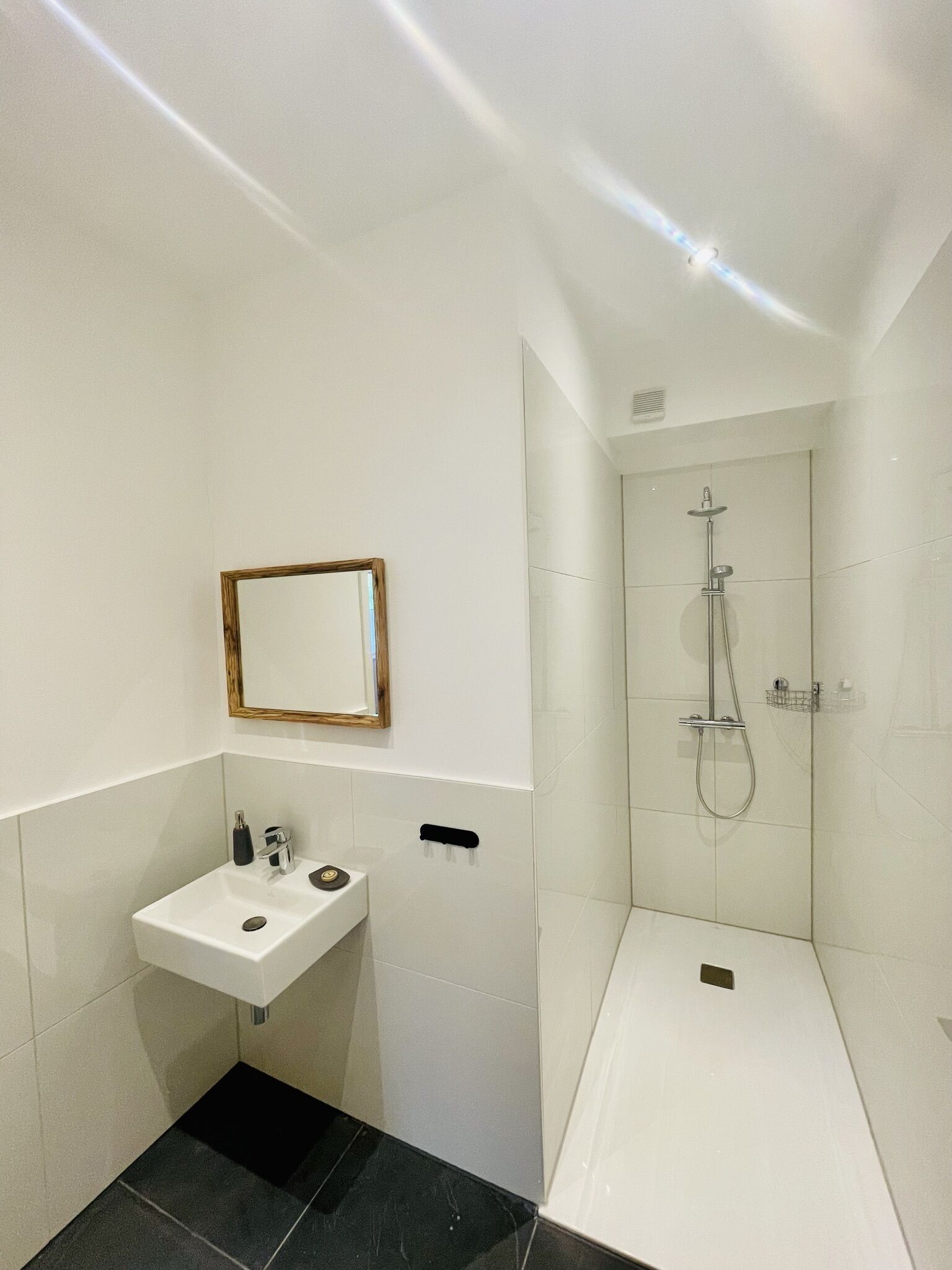 Une salle de bain moderne avec un lavabo blanc, un miroir et une douche.