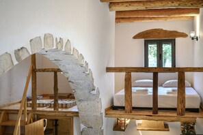 A rustic room with a stone archway, wooden beams, a bed with white linens, and a window with a view of trees. - Nomas house Imbros,Private pool (Imbros)