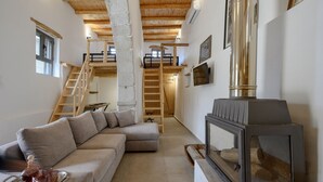 A cozy living room with a wooden staircase, a fireplace, and a modern sofa. - Nomas house Imbros,Private pool (Imbros)