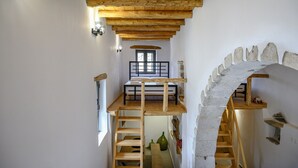 A narrow hallway with a wooden loft bed, a stone archway, and a small window. - Nomas house Imbros,Private pool (Imbros)