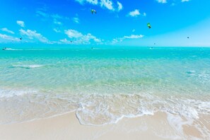 Ein Strand mit klarem türkisblauem Wasser, sanften Wellen und einem sandigen Ufer.