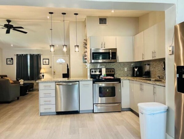 Enjoy cooking in this well-equipped kitchen with a microwave, oven, and dishwasher, adjacent to a cozy living area.