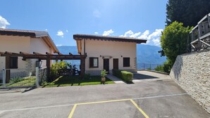Un edificio con una pérgola, un pequeño jardín y vistas a las montañas.
