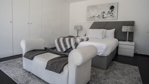 A modern bedroom with a bed, a sofa, a nightstand, and a painting on the wall. - Casa da Magnólia (Briteiros (Santo Estêvão))