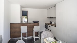 A modern kitchen with a wooden island, white bar stools, and a dining table with glassware. - Casa da Magnólia (Briteiros (Santo Estêvão))