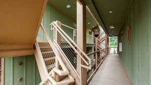 A corridor with beige railings and green walls, leading to multiple levels.