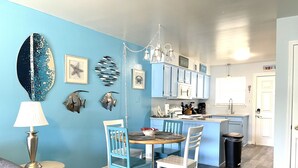 Una cucina con mobili azzurri, una zona pranzo con un tavolo rotondo e sedie, e un lampadario.