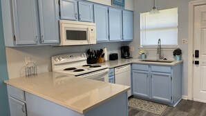 Una cucina con mobili azzurri, un fornello bianco, un forno a microonde e una macchina per il caffè.