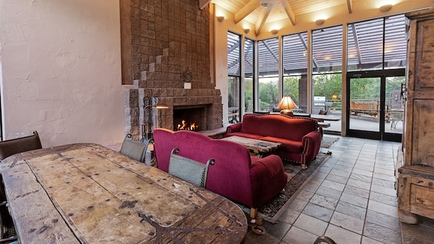 Una habitación amplia con una gran mesa de madera, sofás tapizados en rojo y una chimenea de piedra.