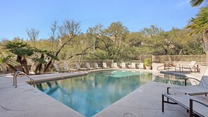 Una piscina con sillas de descanso y palmeras.