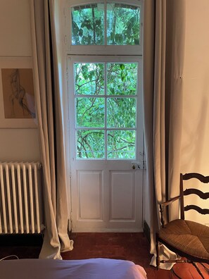 A room with a white door, a radiator, a chair, and a painting on the wall.
