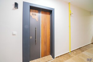A modern door with a number plate, a wall-mounted light, and a yellow pipe.