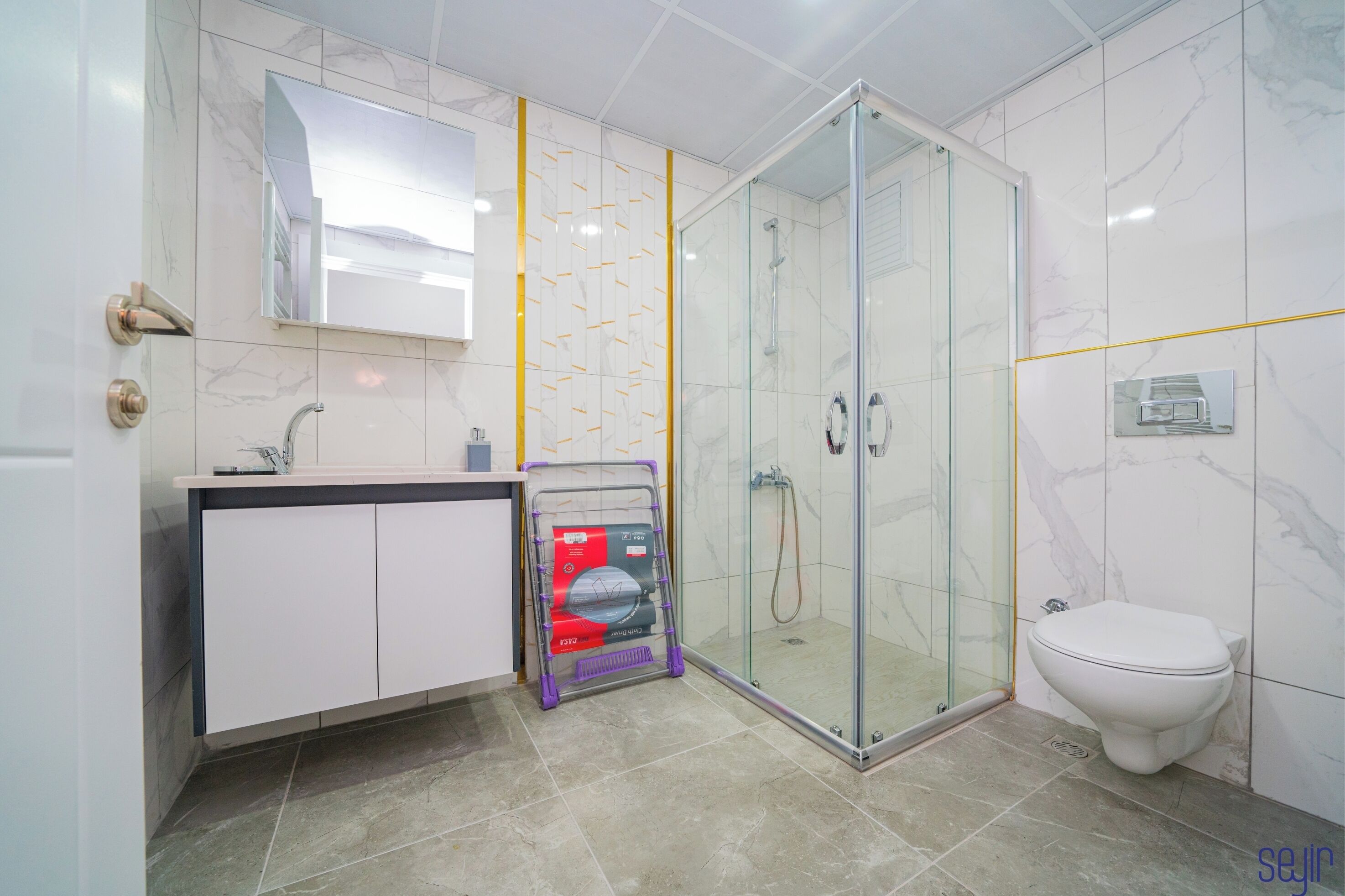 Un baño moderno con cabina de ducha de vidrio, inodoro blanco y tocador con espejo.