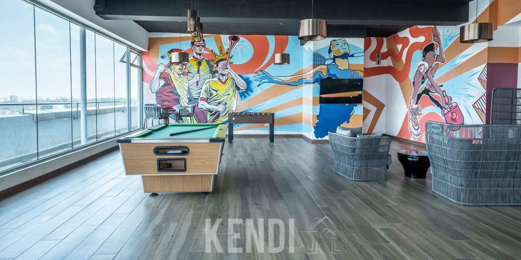 A games room with a pool table, lounge chairs, and a mural.