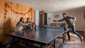 Una mesa de ping pong en una habitación con paredes de madera y un sofá.