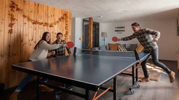 Una mesa de ping pong en una habitación con paredes de madera y un sofá.