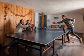 A ping pong table in a room with wooden walls and a sofa.