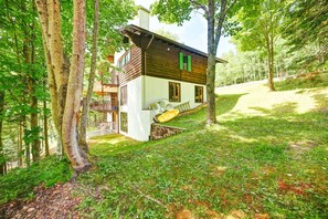 Una cabaña con balcón, rodeada de árboles.