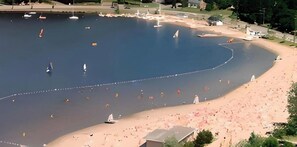 A large body of water with multiple boats and a sandy beach area.