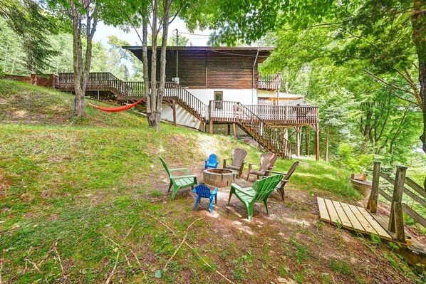 A cabin with a deck, outdoor seating, and a fire pit.