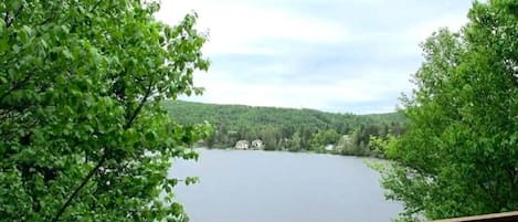 Un lac avec une terrasse en bois et des arbres au premier plan.