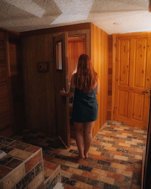 Una persona caminando por un pasillo con puertas de madera y piso estampado.