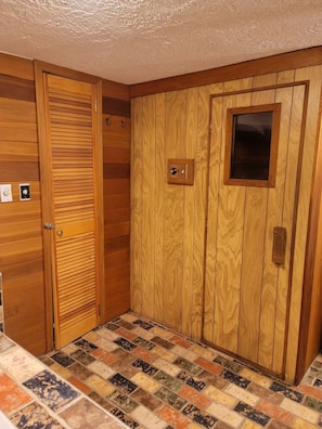Una habitación con paredes de paneles de madera, suelo de baldosas y una puerta con ventanal.