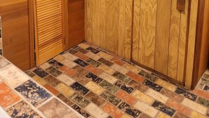 Una habitación con paredes de paneles de madera, suelo de baldosas y una puerta con ventanal.