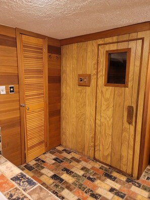 A room with wooden panel walls, a tiled floor, and a door with a window.
