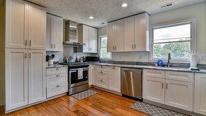 A modern kitchen with white cabinets, stainless steel appliances, and hardwood flooring. - Aiken Rd - 6 BR - hot tub and game room (Asheville)