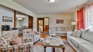 A living room with a coffee bar, two sofas, a dining area, and a staircase. - Aiken Rd - 6 BR - hot tub and game room (Asheville)