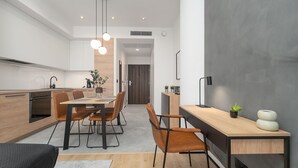 Een moderne keuken met houten kasten, een eethoek met een houten tafel en stoelen, en een klein werkgedeelte met een bureau en stoel.
