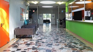 A hallway with a patterned floor, a reception desk, and a seating area with a couch. - Hi! Ostello Milano (Milan)