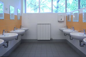Des toilettes publiques équipées de quatre lavabos, de miroirs et d’un radiateur.