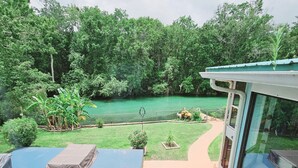 Un espace extérieur abrité offrant une vue sur un paysage verdoyant et une étendue d’eau.