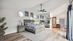 Une chambre avec un grand lit, un ventilateur de plafond et une fenêtre.
