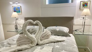 A neatly made bed with star-patterned bedding, two swan-shaped towels, and a heart-shaped towel arrangement. - Top Location, Stylish Apartment, City Center, Nearby Parking, Bus/train Station (Ljubljana)