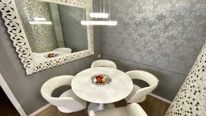 A dining area with a round table, white chairs, a decorative mirror, and patterned wallpaper. - Top Location, Stylish Apartment, City Center, Nearby Parking, Bus/train Station (Ljubljana)